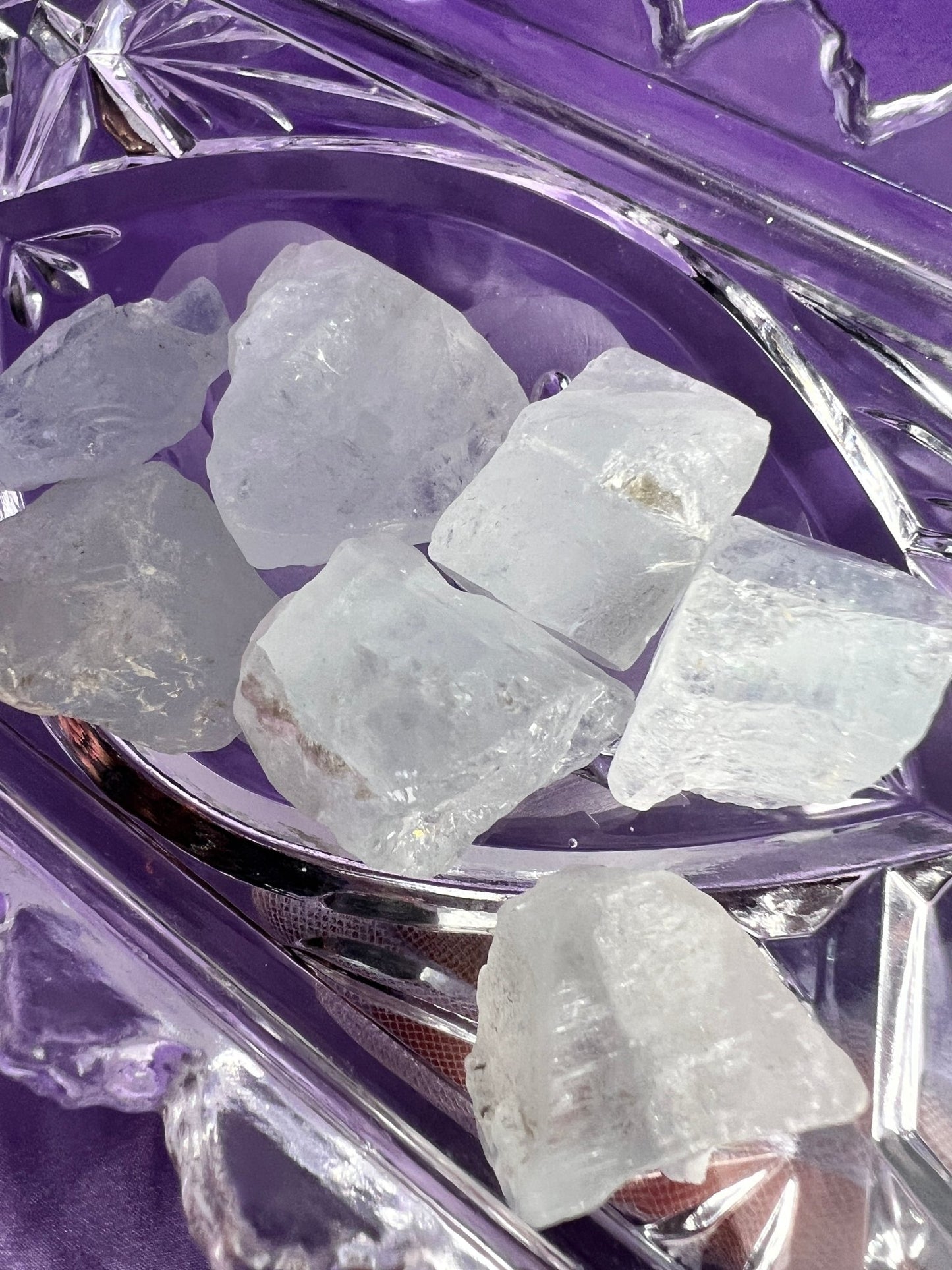 aquamarine on a crystal dish on a lavender colored cloth.