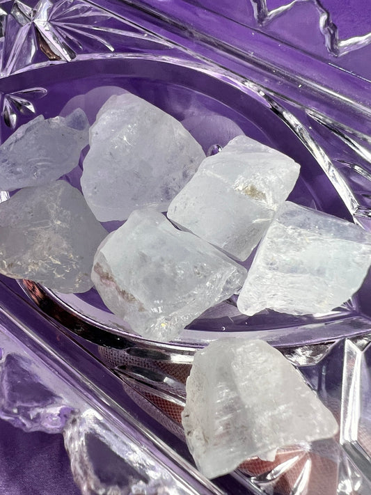 aquamarine on a crystal dish on a lavender colored cloth.